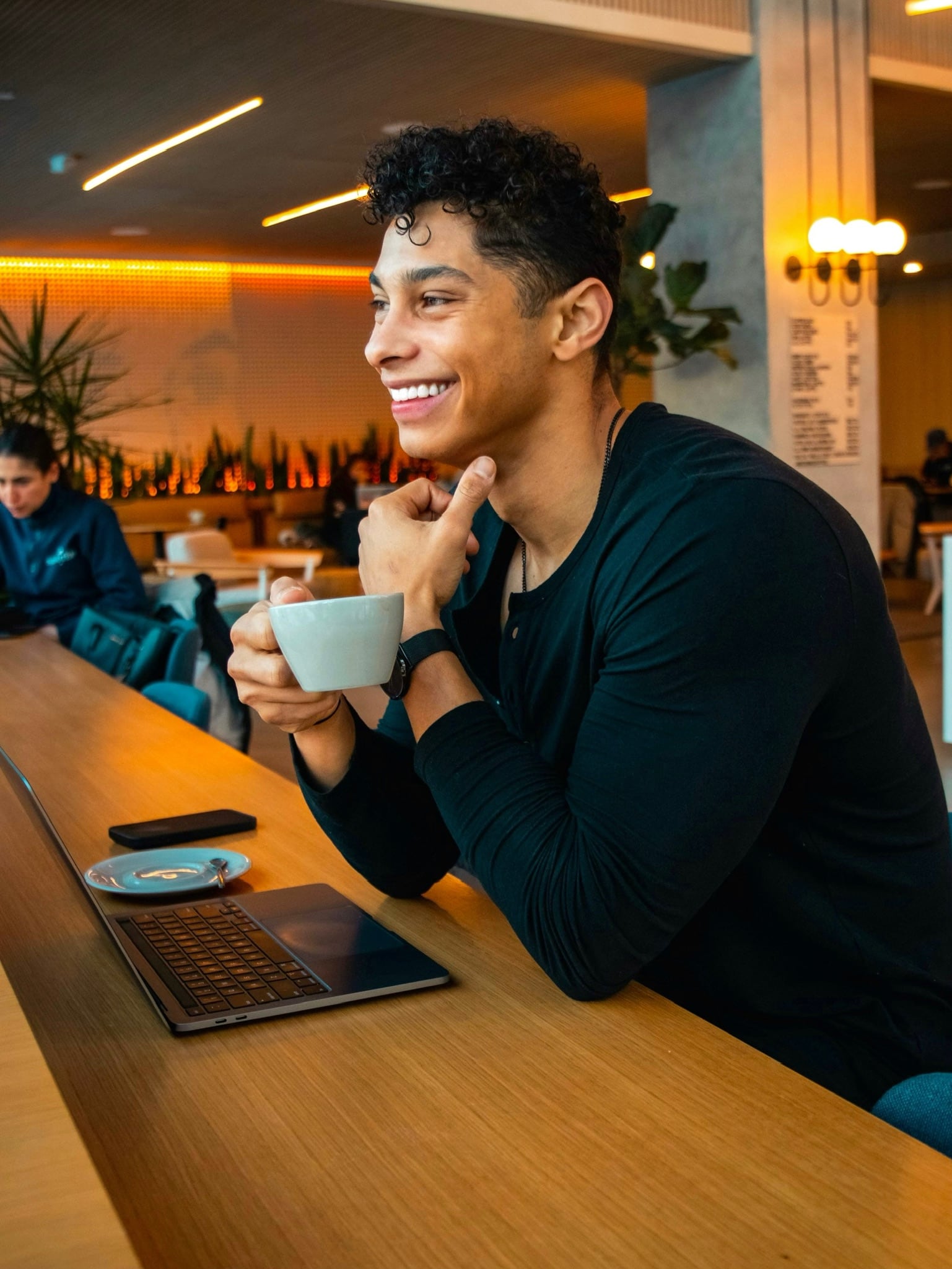 Coach sitting in a cafe with his laptop.